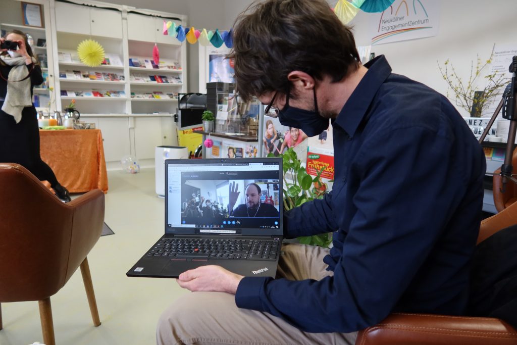 Das Bild zeigt den NEZ-Mitarbeiter Lukas Schulte und einen Laptop mit einer laufenden Videokonferenz.