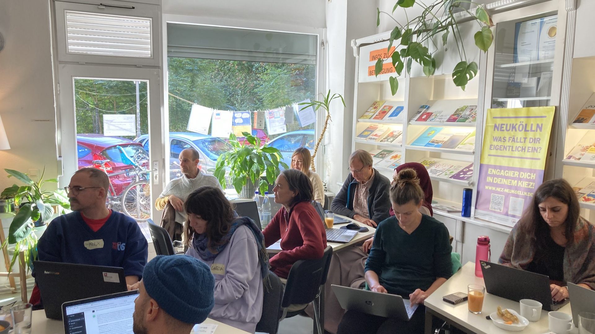 10 Menschen sitzen in einem hellen Raum an ihren Computern, während sie an einem Workshop teilnehmen.